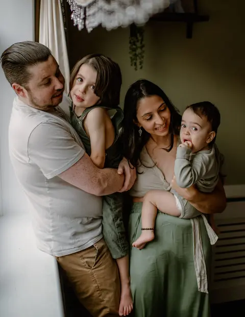 Parents holding their two young children by a window