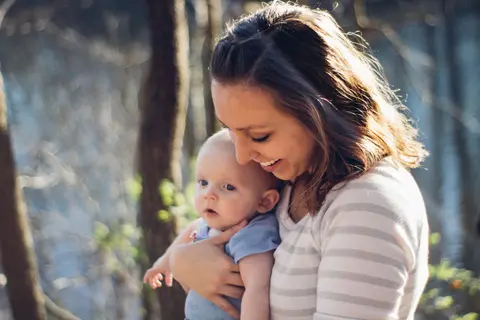 A mother smiling at the baby in her arms