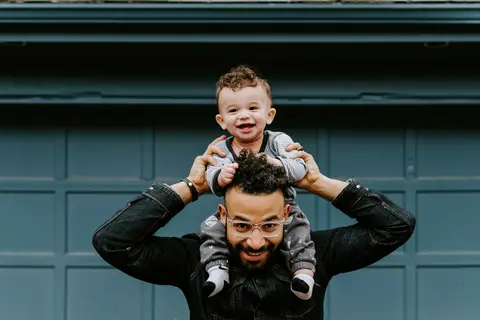 A smiling father carrying his baby on his shoulders